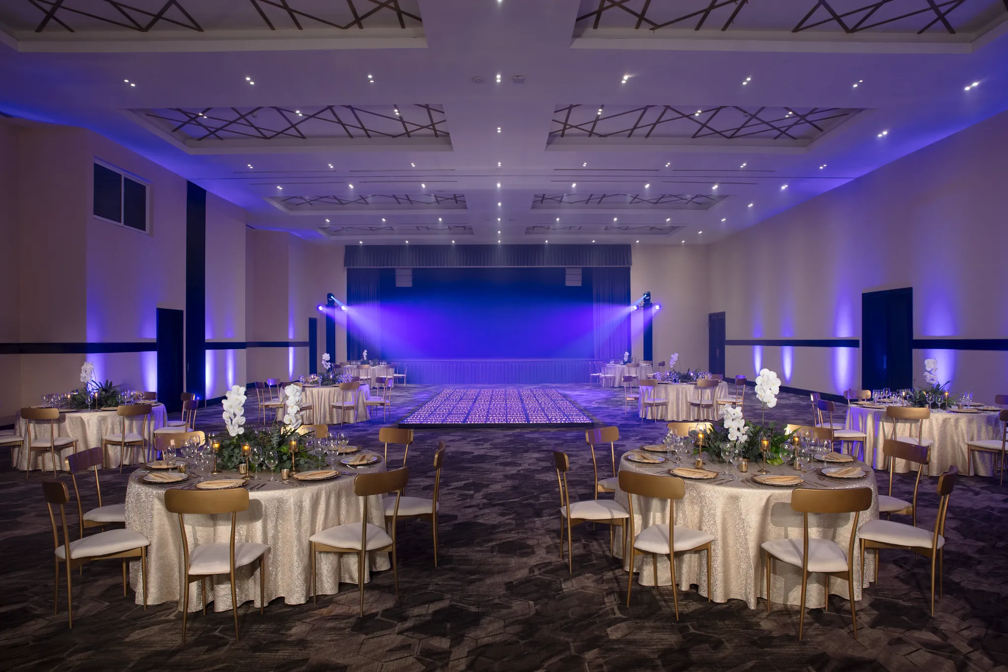 Elegant ballroom wedding reception setup with dance floor and stage lighting at Dreams Riviera Cancun