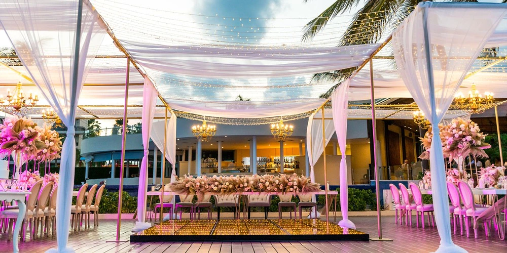 Elegant deck wedding reception setup with draped canopy and string lights at Dreams Riviera Cancun