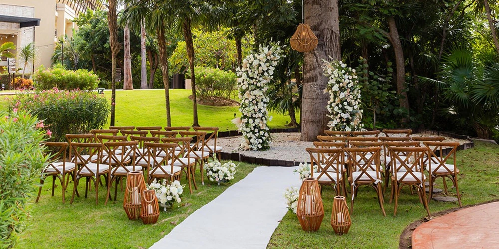 Garden wedding ceremony setup with floral arch under trees at Mayan Tree venue at Dreams Riviera Cancun