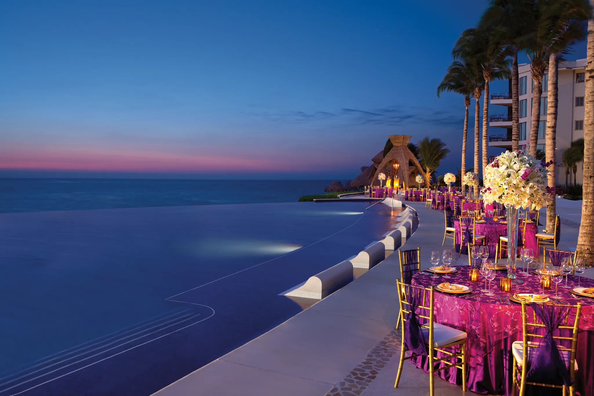 Pool terrace wedding reception setup with ocean views at sunset at Dreams Riviera Cancun