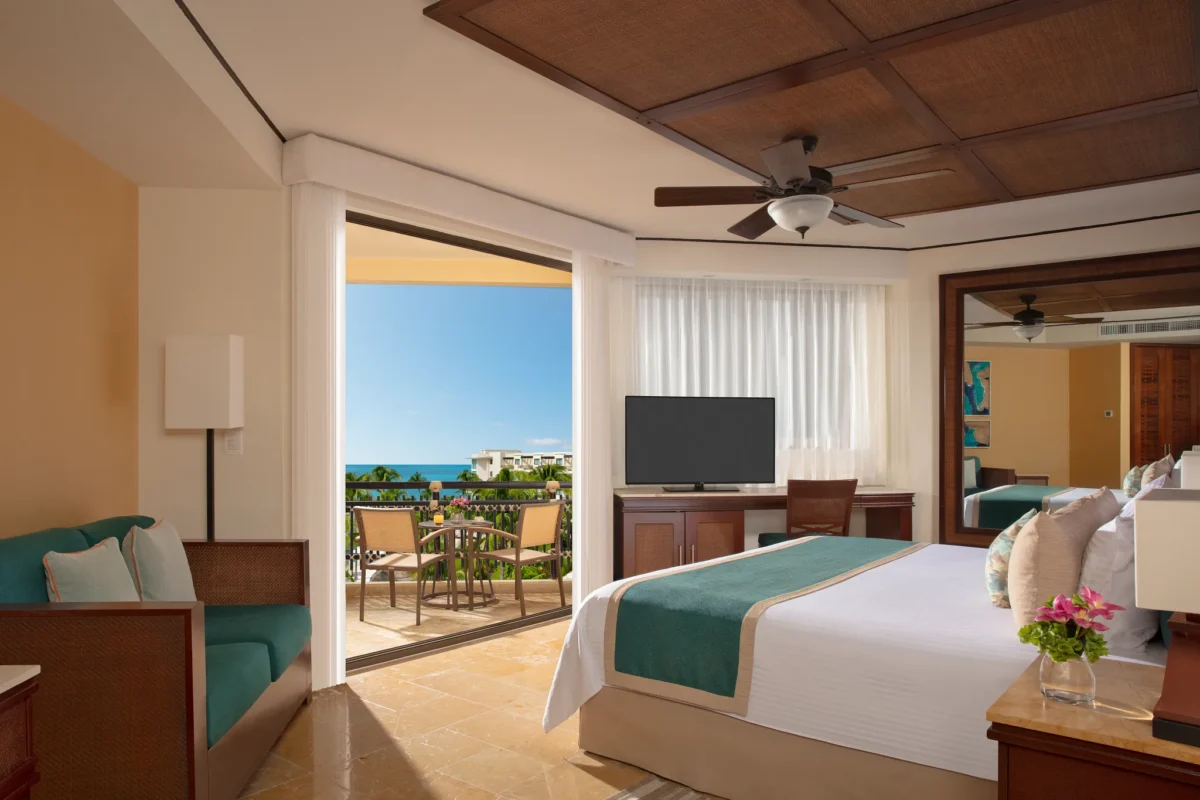 Premium Deluxe Ocean View suite with king bed and open balcony doors overlooking the ocean at Dreams Riviera Cancun.