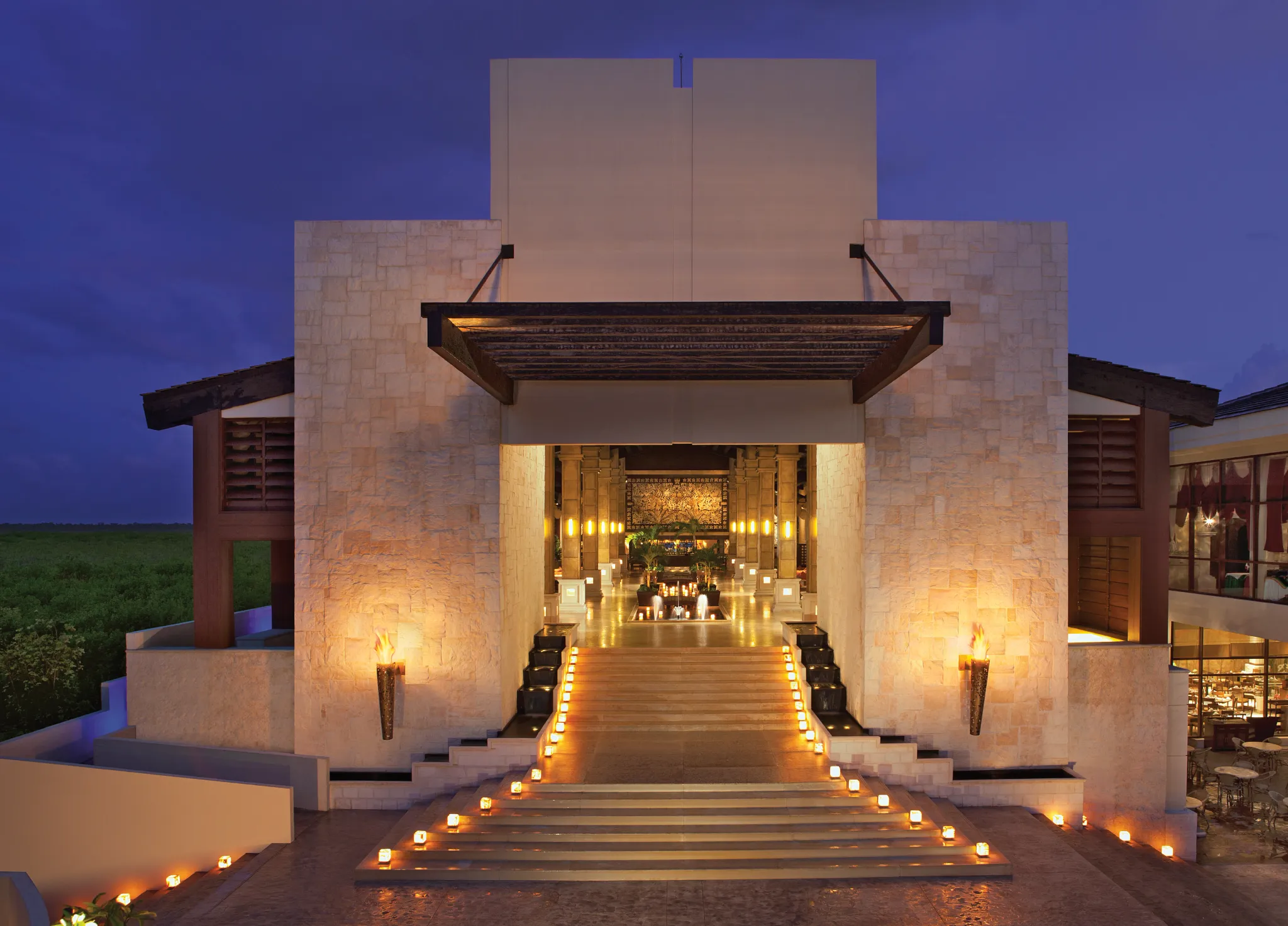 Illuminated resort entrance with candles at Dreams Riviera Cancun Resort & Spa at night.