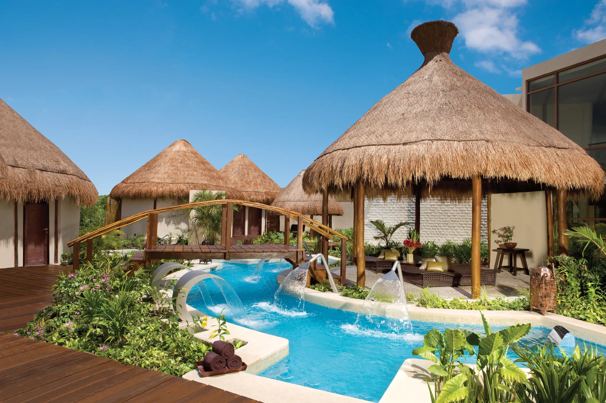 Tropical spa garden with hydrotherapy pools and thatched palapas at Dreams Riviera Cancun Resort & Spa.